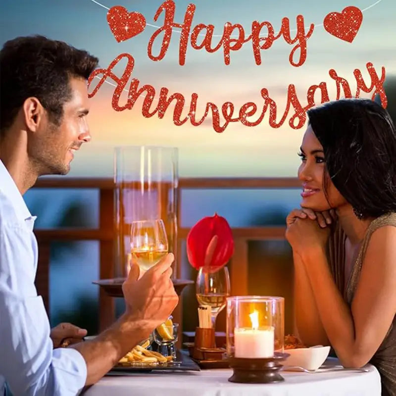 Glittery red happy anniversary banner with heart decorations made of glitter material for party decoration and celebration.