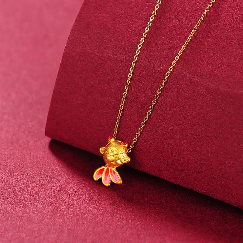 Collier pendentif poisson en or 24 carats, doté de nageoires émaillées roses et d’yeux sertis de pierres rouges.