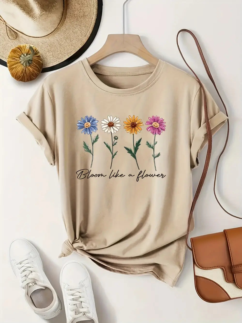 camiseta casual de manga corta color beige confeccionada con una tela suave, con un diseño floral colorido de cuatro florecillas y la frase bloom like a flower impresa debajo.
