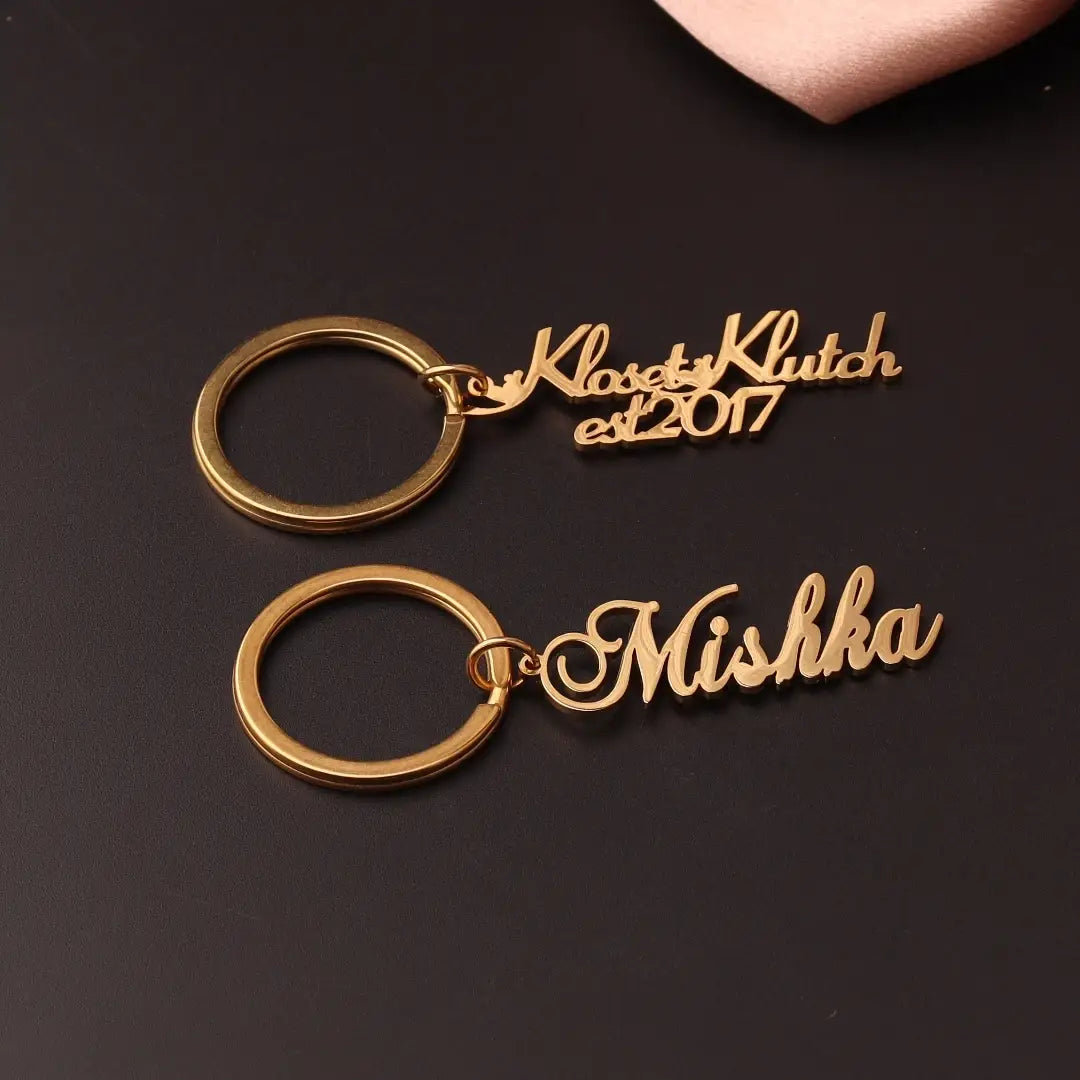 Gold-colored stainless steel custom name keychains engraved with kloset klutch est 2017 and mishka, designed as personalized gifts.