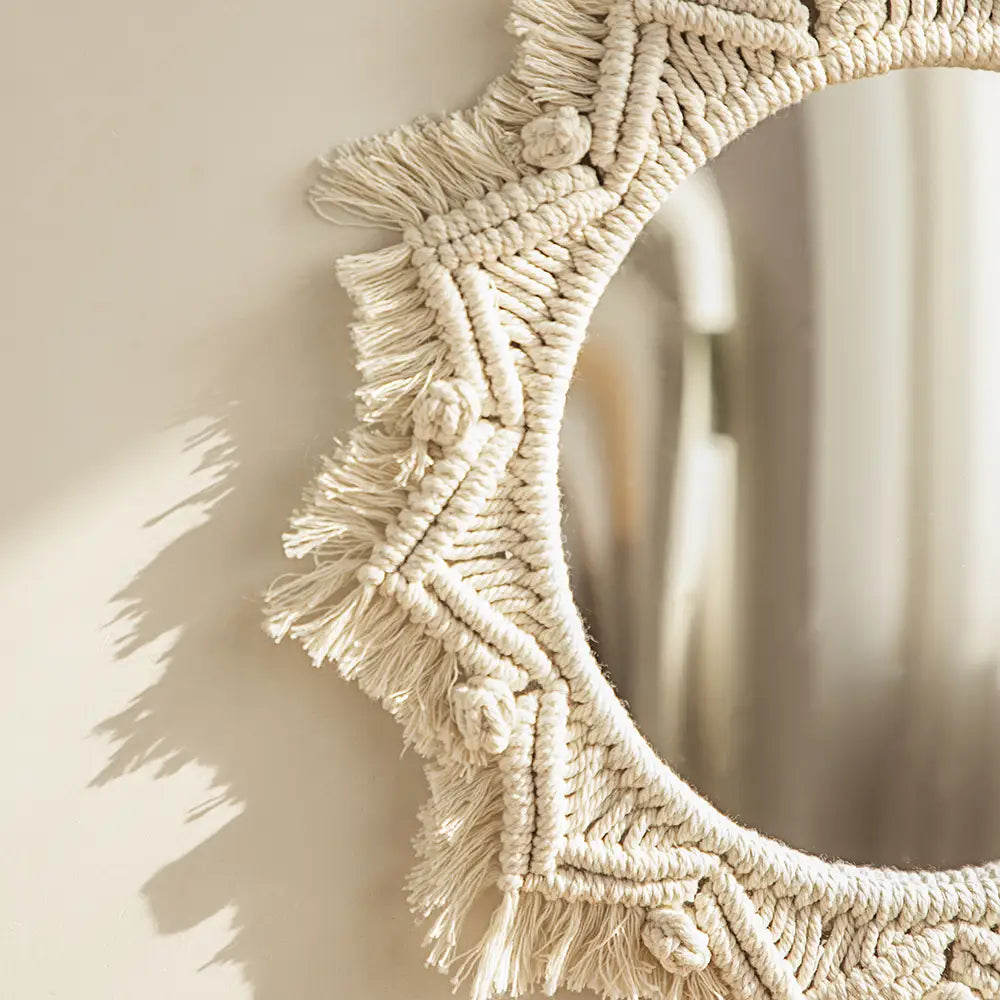 Cream-colored macrame wall mirror with intricate knotwork and fringe detailing for living room home decor.