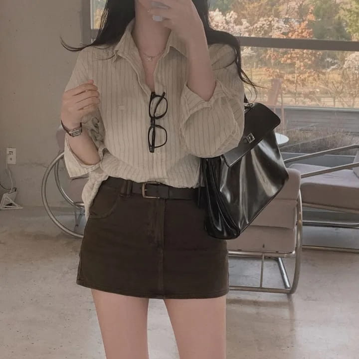 Black patent leather handbag with a structured shape and silver-toned hardware complementing a versatile style striped long sleeve button down shirt with standard thickness and a striped pattern.