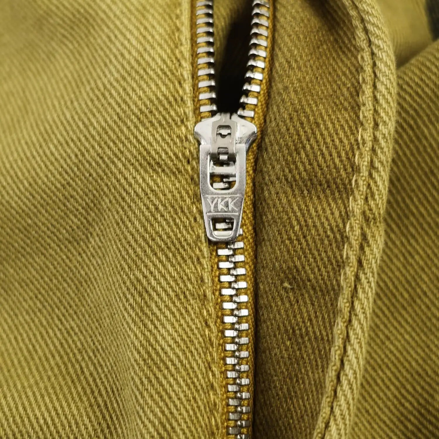 Silberner YKK-Reißverschluss mit metallischen Zähnen und Zuglasche, in olivgrünen Webstoff an Hosen mit weitem Bein, Polka-Dot und hoher Taille eingenäht.