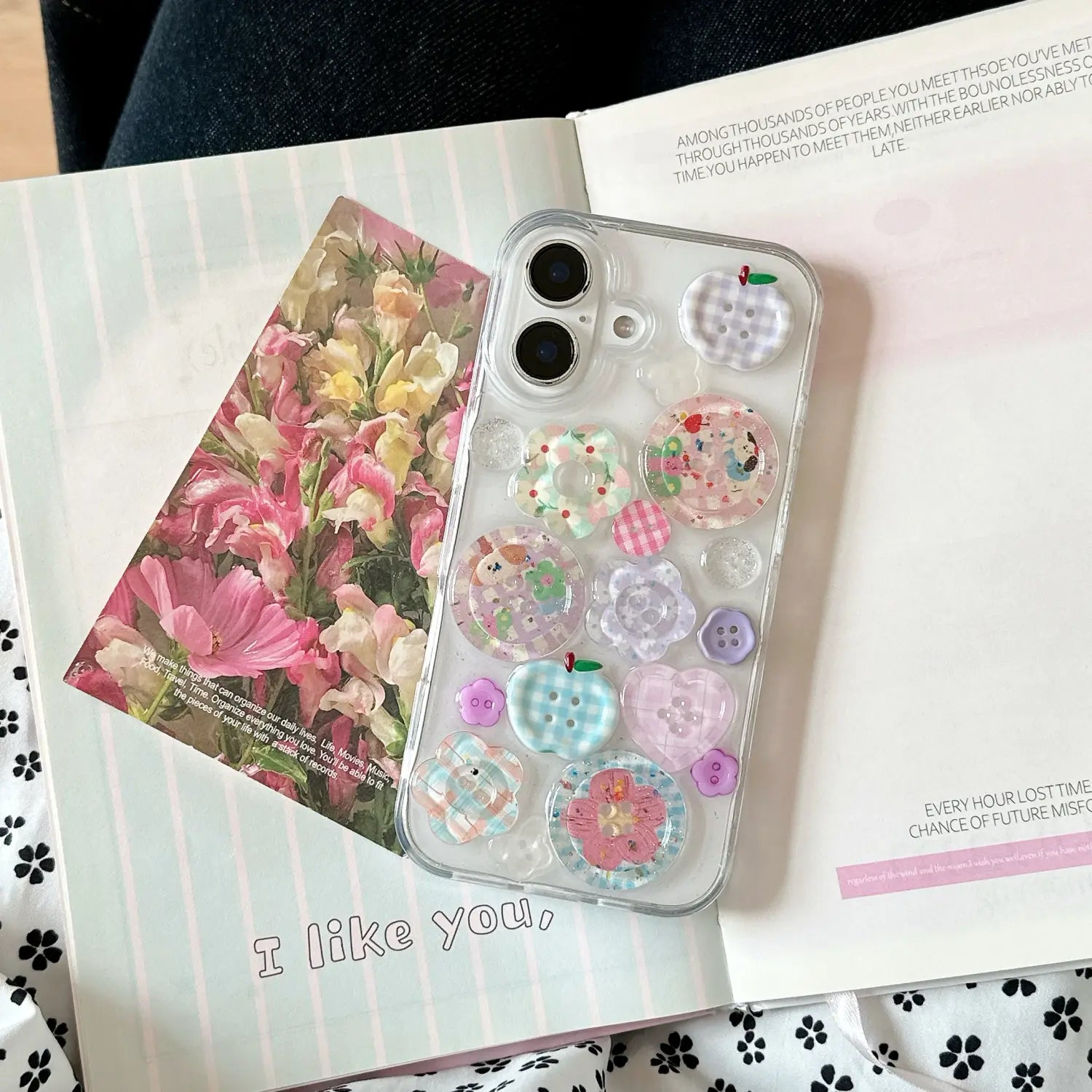 Funda transparente para teléfono vista desde la parte posterior, adornada con encantos de botón translúcidos y coloridos en tonos pastel de rosa, azul y morado para iPhone.