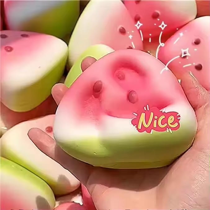 Un jouet antistress « squishy » en forme de pastèque, rose et vert, avec des détails de graines rouges, ainsi qu’une belle étiquette visible sur la face avant, pour soulager le stress.