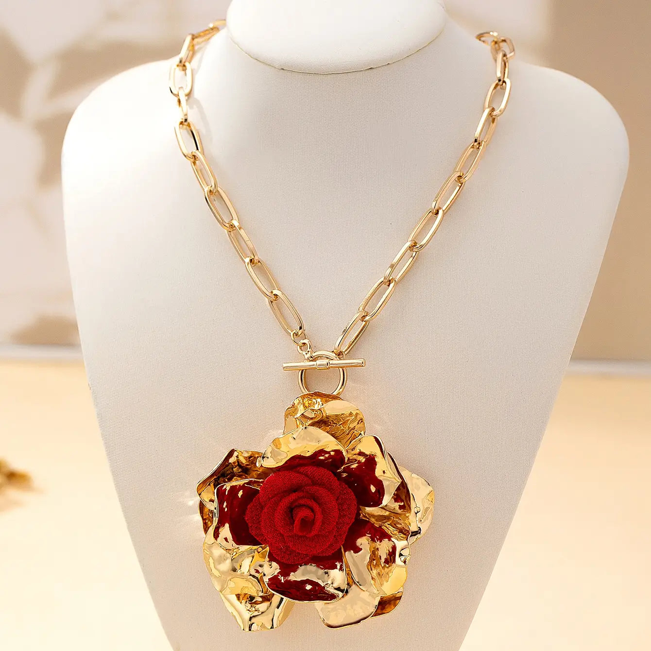 Gold chain necklace with a large textured gold-toned rose pendant featuring a vibrant red fabric center from the red floral jewelry set gold rose necklace and earrings.
