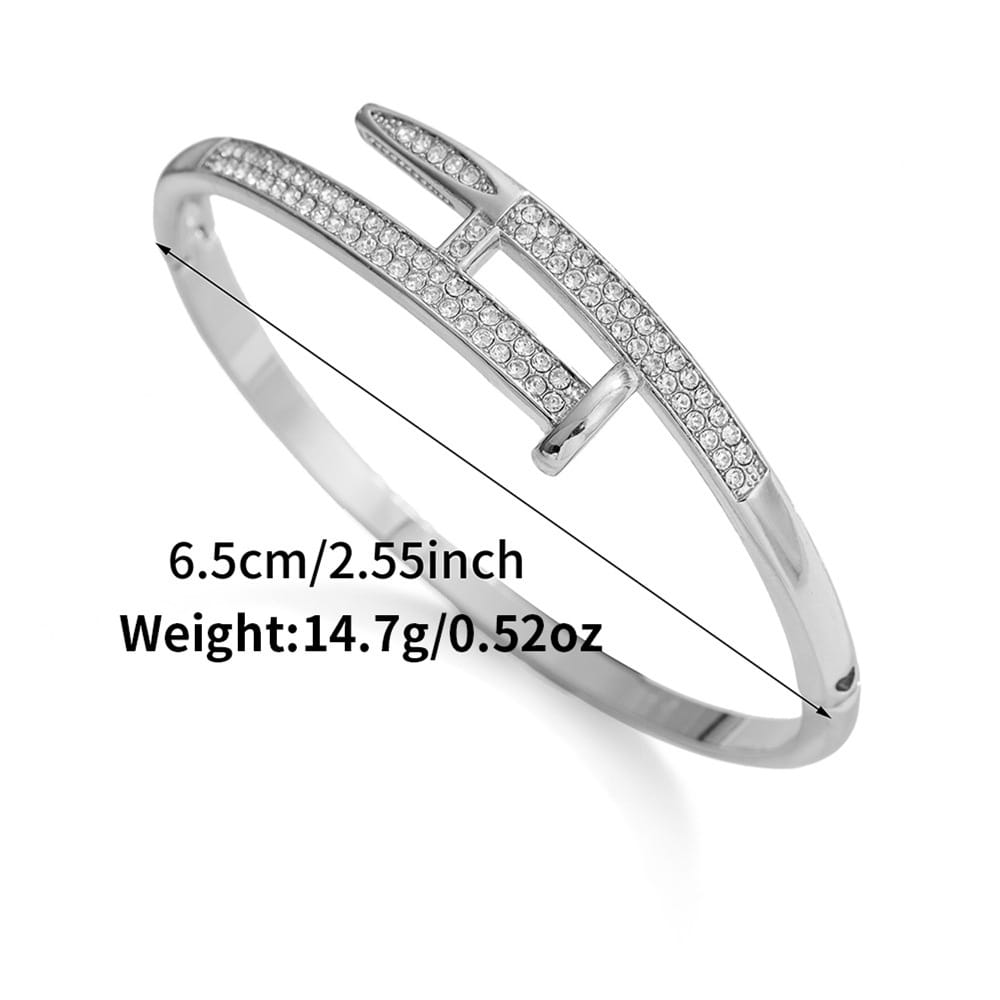 Bracelet jonc en zirconium cubique intersectant à tons argent, présentant un design géométrique audacieux avec des cristaux transparents intégrés le long de sa longueur.