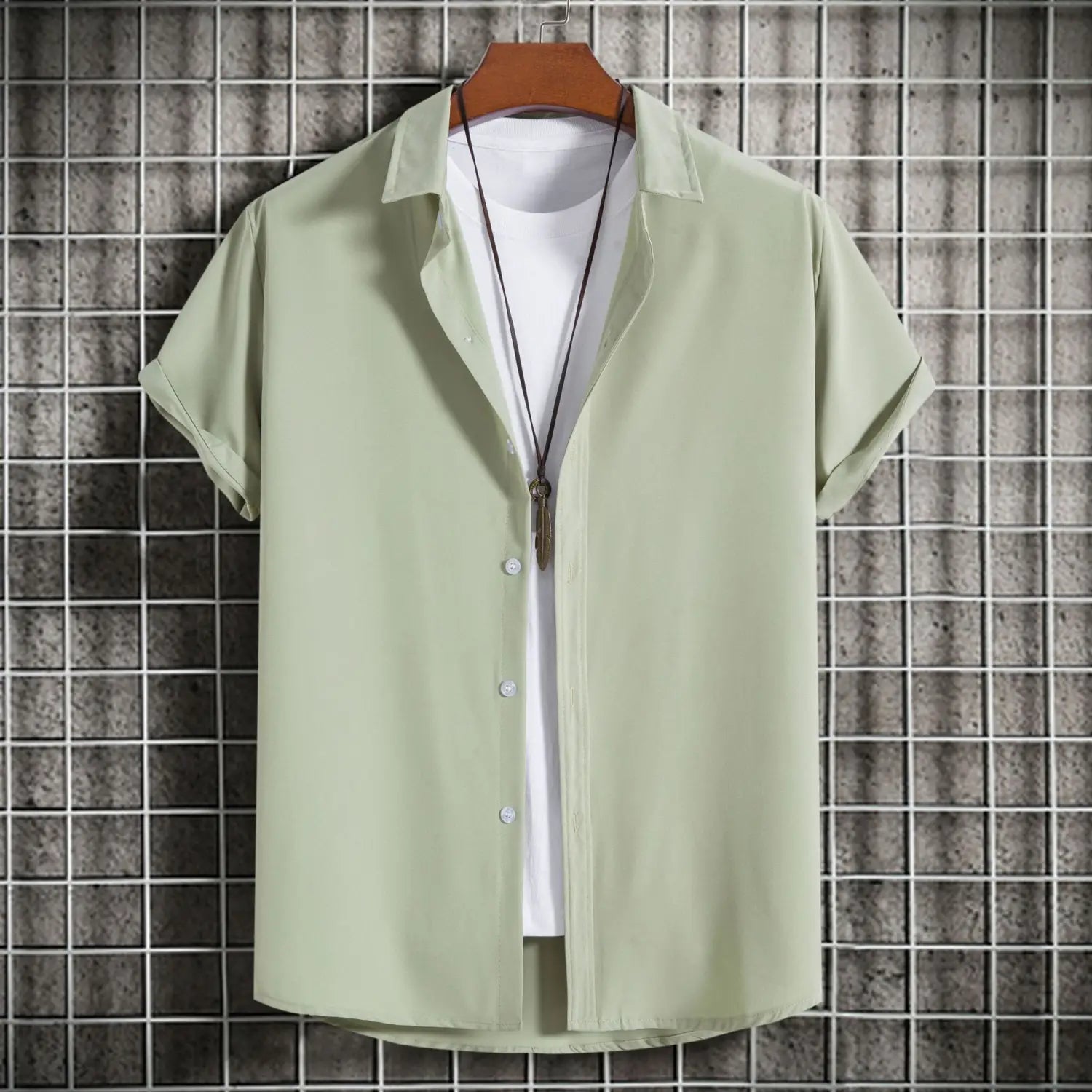 Chemise à manches courtes vert clair pour homme, style mode, unie, suspendue à un cintre en bois, convenant comme chemise de plage décontractée.