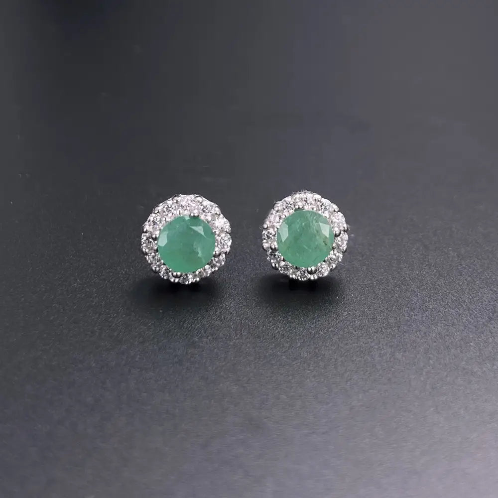 Elegant emerald green gemstone stud earrings with a halo of sparkling diamonds set in silver-toned metal from the emerald sterling silver jewelry set.