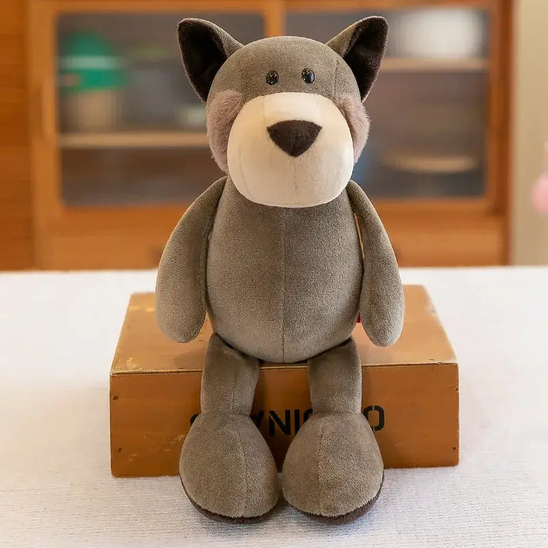 un animal de peluche lobo suave gris, con orejas negras, hocico blanco y nariz color marrón oscuro, en una colección que incluye juguetes blandos de león, elefante y tigre, y perros de elefante y tigre