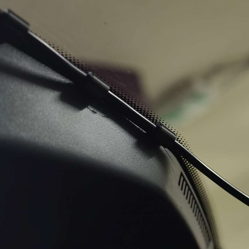fermeture éclair noire dotée d’une languette de traction perforée texturée sur une surface en tissu gris foncé du tableau de bord de voiture, pour des organisateurs de câbles à emboîtement s’emboîtant l’un dans l’autre.