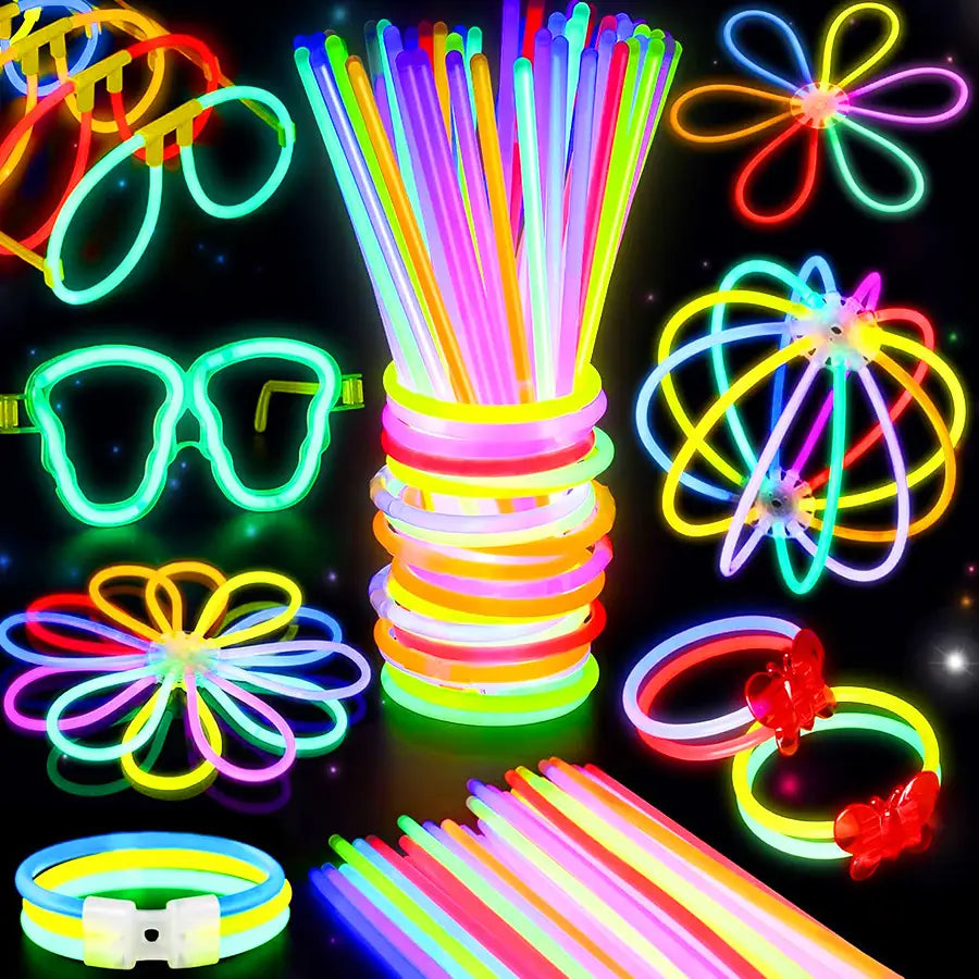 Una variedad vibrante de bastones luminosos de neón a granel, collares y pulseras para fiestas, con colores neón luminosos en diversas formas, que incluyen pulseras, monturas de gafas, diseños florales y una torre central de tubos de colores.