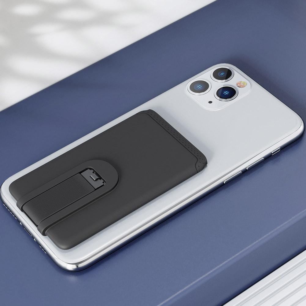 Black magnetic phone card holder with textured grip and snap mechanism attached to the back side of a silver mobile phone silicone stick-on wallet universal black.