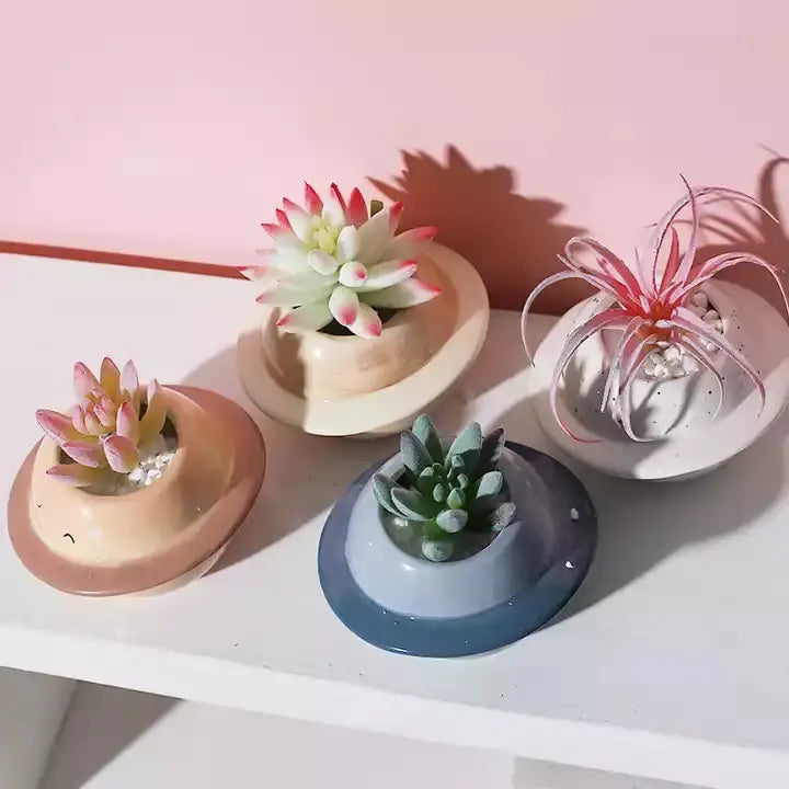 Vier Miniatur-Keramik-Sukkulenten-Töpfe mit einzigartigen pastellfarbenen Glasuren, die verschiedene kleine Pflanzen für die Verwendung auf dem Schreibtisch aufnehmen.