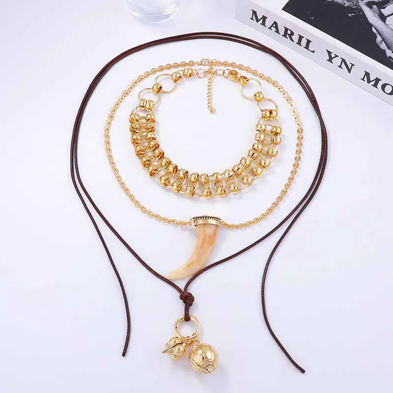 Vintage ethnic layered pendant necklace for women featuring a gold-toned layered design with a prominent tusk pendant and decorative beads on braided cord.