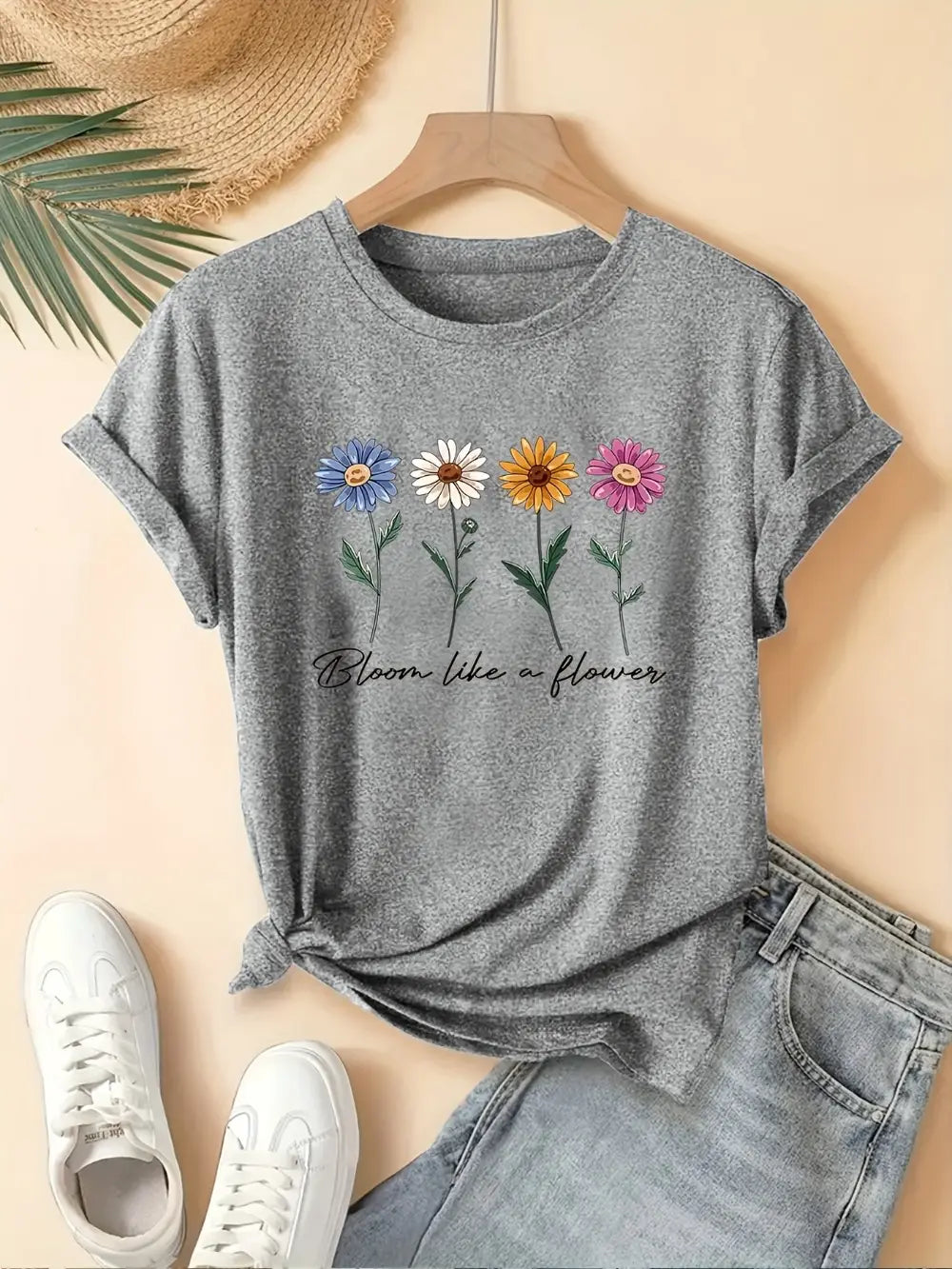 camiseta casual de manga corta de algodón jaspeado gris con estampado floral, con flores coloridas y la frase bloom like a flower en un estilo caligráfico negro.