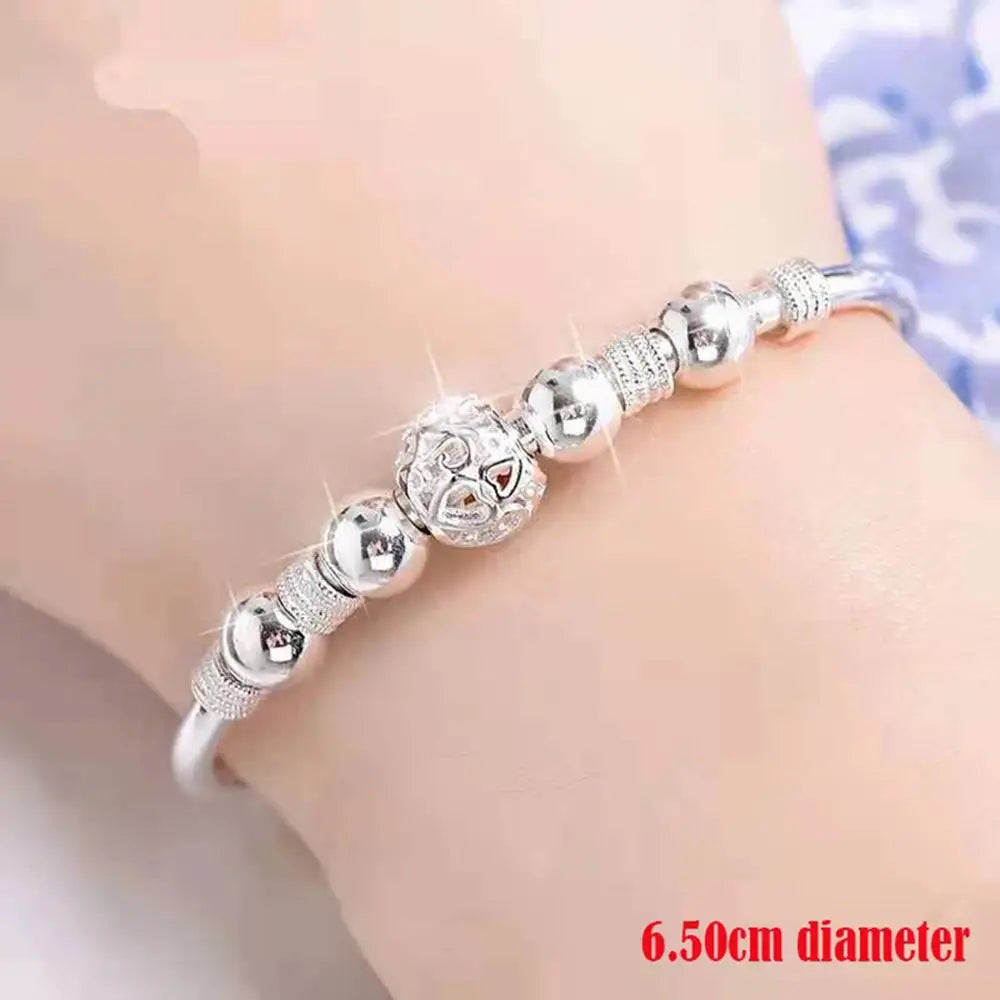 Sterling silver beaded bangle bracelet for women featuring an exquisite beaded design with a central ornate bead embedded with a red gemstone and sparkling details, ideal as a party gift.
