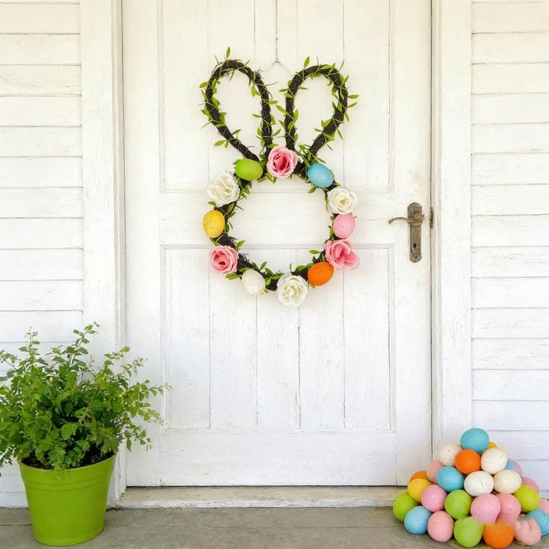 Easter bunny floral wreath for front door made of green vine with colorful artificial roses and painted eggs.