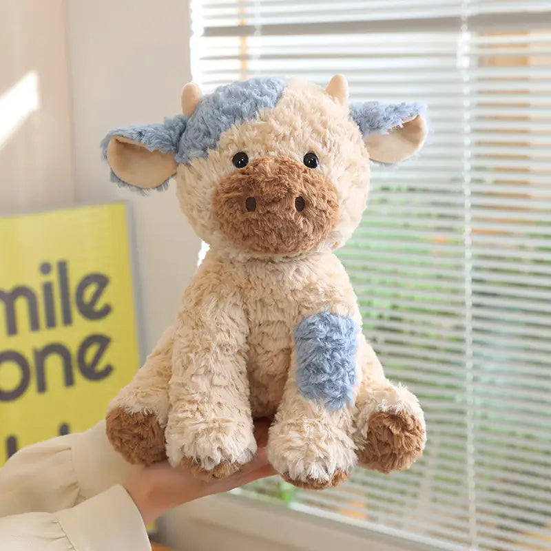 Plush stuffed animal toy 25cm featuring a soft cream-colored fabric with blue patches on the head and paw and brown snout and ears.