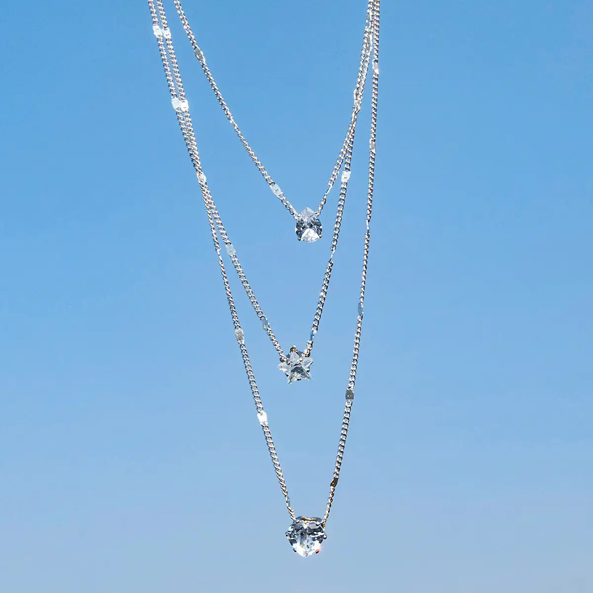Silver zircon layered pendant necklace for women with three dangling star-shaped crystal pendants.