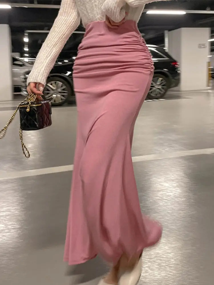 Ein zarter rosafarbener Meerjungfrauen-Midirock mit geraffter, hoher Taille, fließendem Stoff und einem strukturierten Bund.