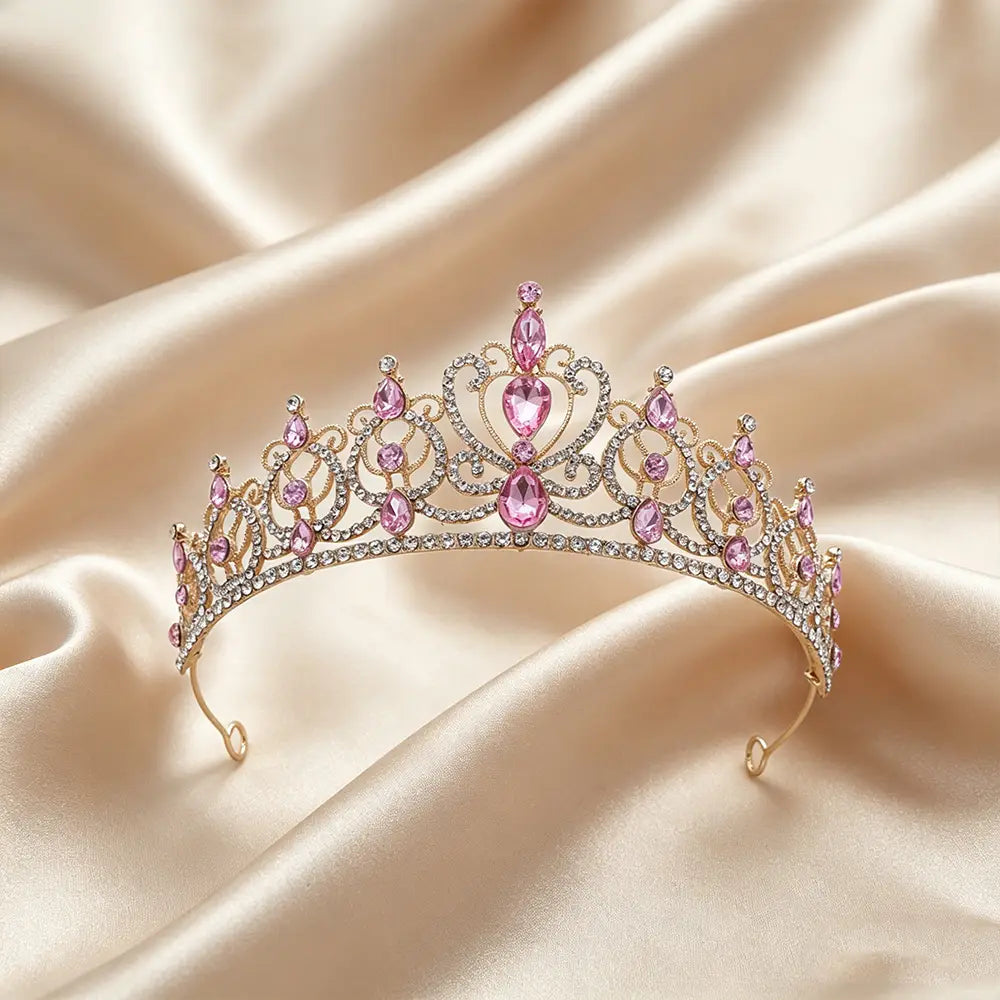 Une délicate couronne de diadème baroque en strass doré, sertie de cristaux roses étincelants et de cristaux transparents, dans un motif ornemental en forme de cœur, destinée à servir d’accessoire de coiffure de mariée.