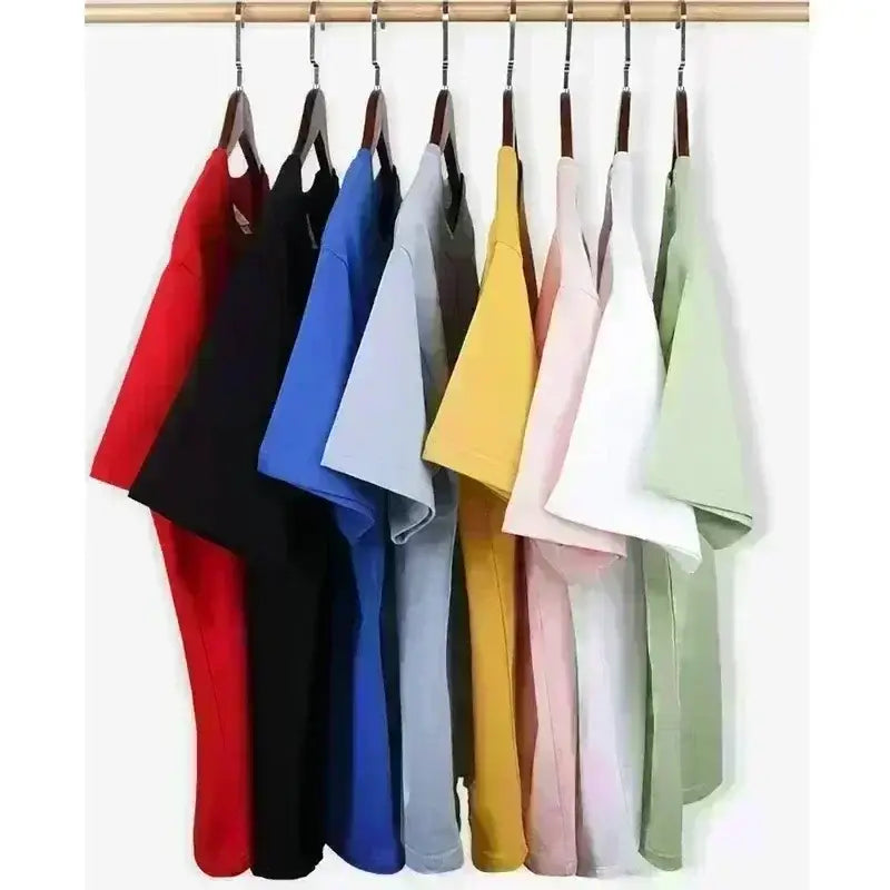 Una fila de camisetas deportivas de verano unisex en colores sólidos rojo, negro, azul, gris, amarillo, rosa y blanco, colgadas en perchas de madera, que muestran mangas cortas y tejido transpirable.