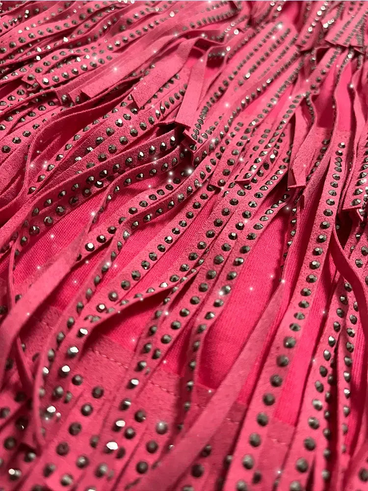 Mini-jupe taille haute fuchsia vif à franges en strass, avec des rangées de clous argentés scintillants le long de chaque lanière.
