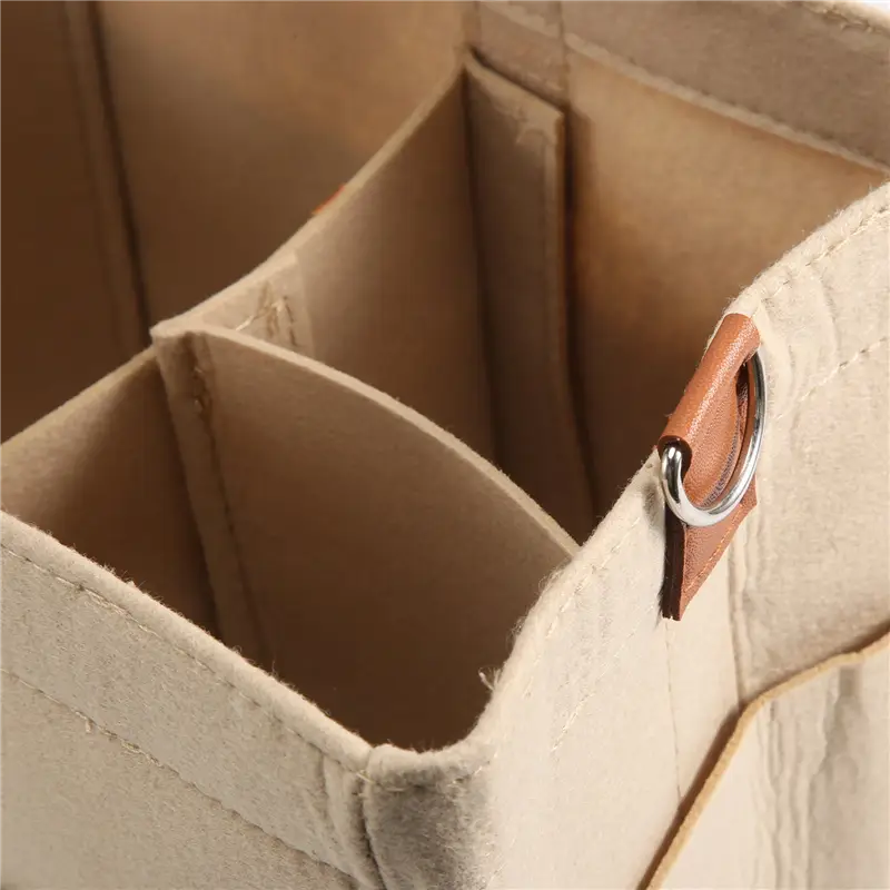 Beige felt baby diaper caddy nursery storage basket with tan leather strap and silver metal ring.