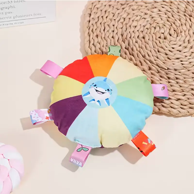 にこやかなサメの顔とカラフルな布製つかみタブを備えた、レインボー色の犬用ぬいぐるみボール玩具。ふわふわした子ども向けの玩具です。