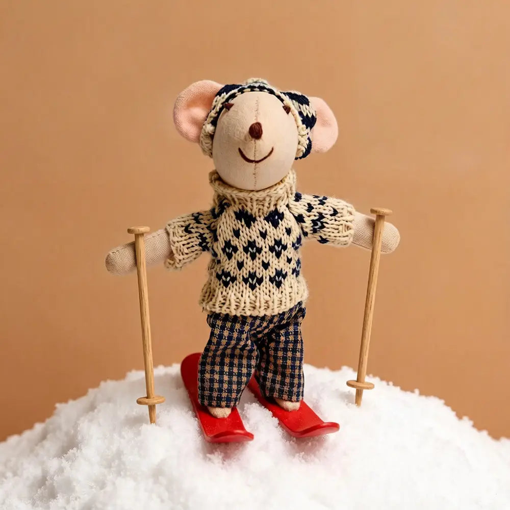 A charming cream and navy blue knitted plush mouse doll stuffed animal toy wearing a matching hat and standing on red skis with wooden poles.