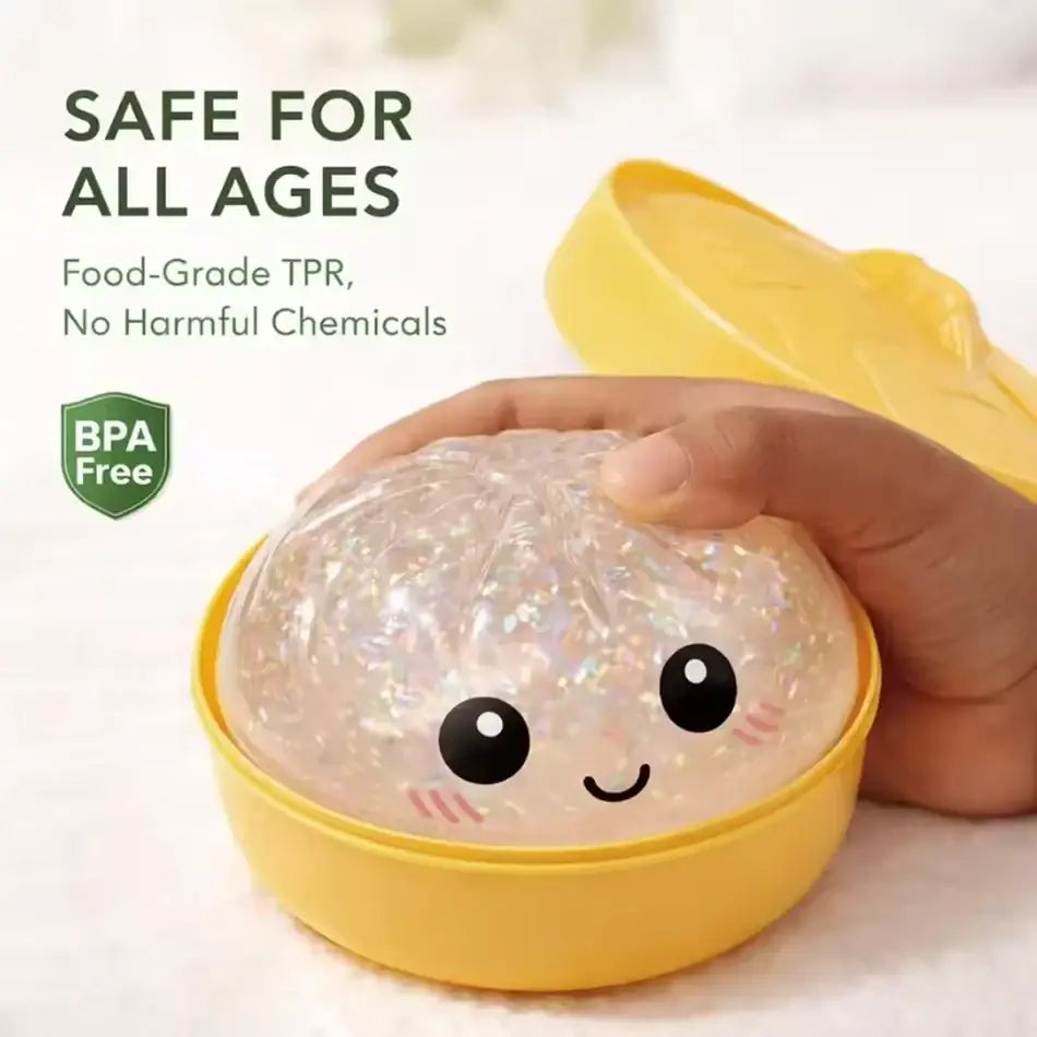 A translucent iridescent brain-shaped glitter dumpling squishy stress relief toy with black eyes in a yellow box