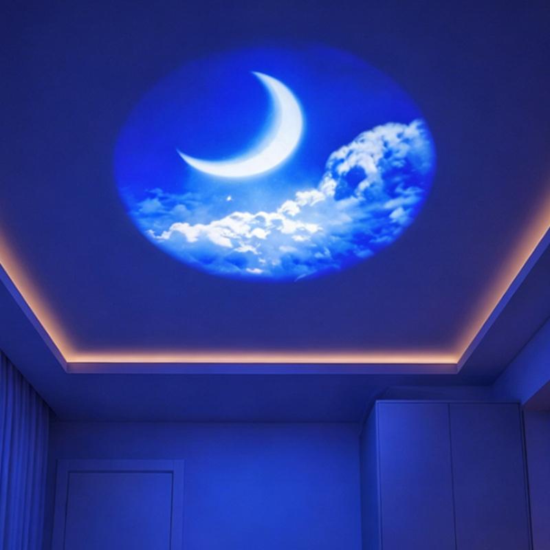 a usb galaxy projector displaying a circular blue ceiling projection with a glowing crescent moon and fluffy white clouds using replaceable projection discs