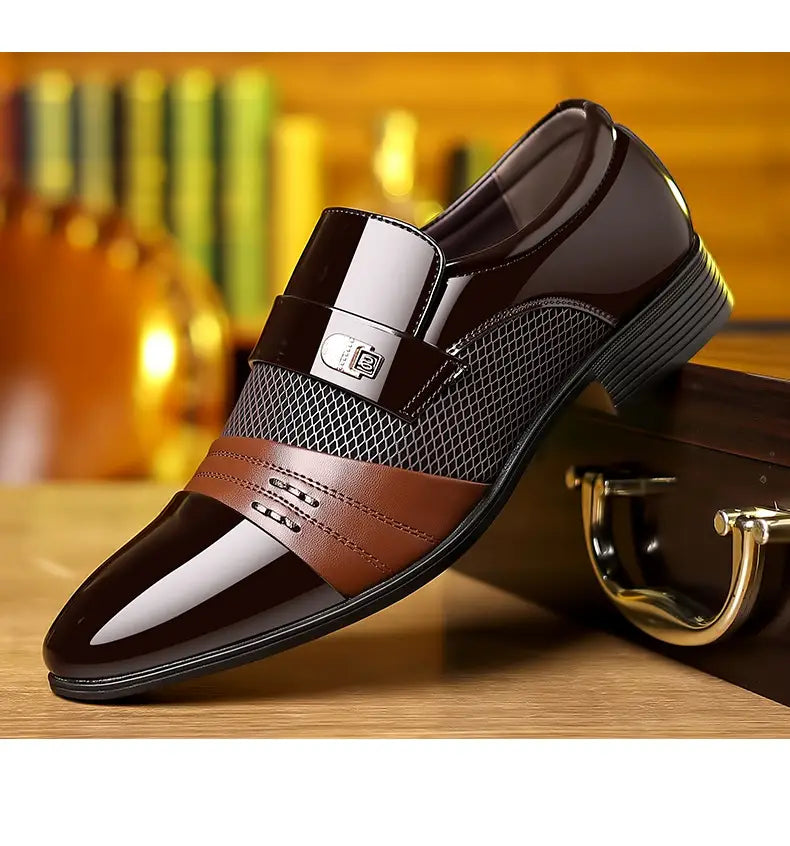 Zapato de vestir de punta afilada de lujo para hombre en cuero marrón y negro brillante, con detalles cosidos en paneles de malla y hebilla plateada.