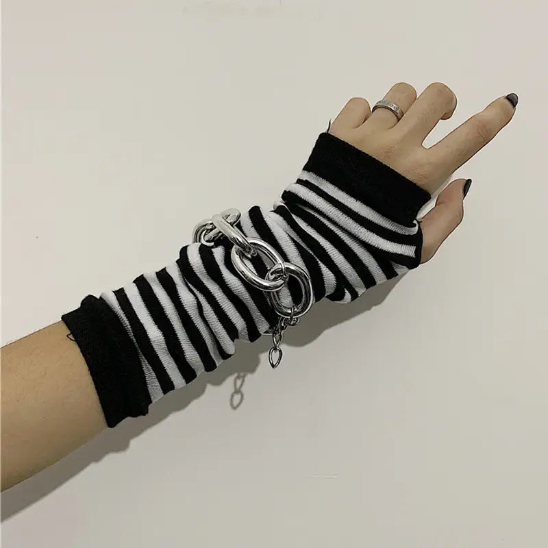 striped knit fingerless arm warmers in black and white stripes paired with a chunky silver chain link bracelet on the wrist