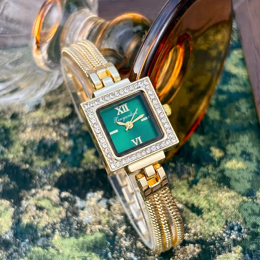 Gold diamond square watch with a gold-toned case, green dial, roman numerals, and diamond-studded bezel featuring a vintage fringe strap.