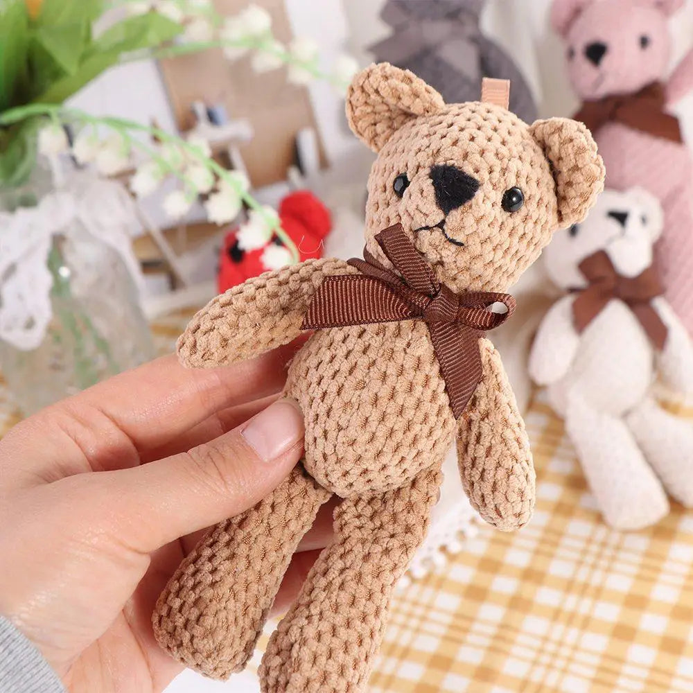 Peluches en forme d’ourson teddy au crochet faites à la main, en laine beige clair, avec des yeux à boutons noirs et un nœud de ruban marron autour du cou.