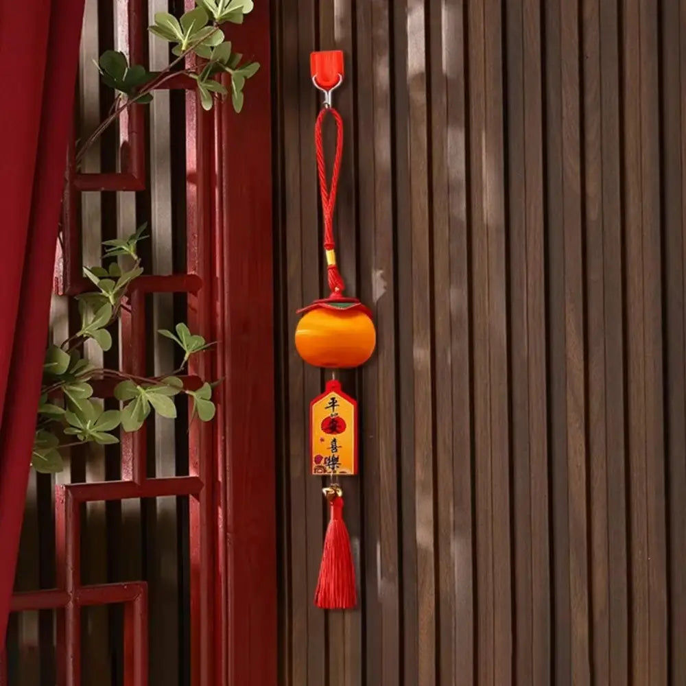 Ein lebhaftes orangefarbenes kugelförmiges Laternenanhänger-Design zum Chinesischen Neujahr 2025 mit roter Quaste und einem hängenden Schild mit chinesischen Schriftzeichen