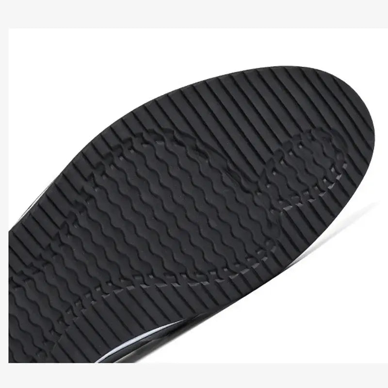 Black rubber sole with a textured wavy tread pattern of men leather slip on driving shoes casual loafers showing the back side.