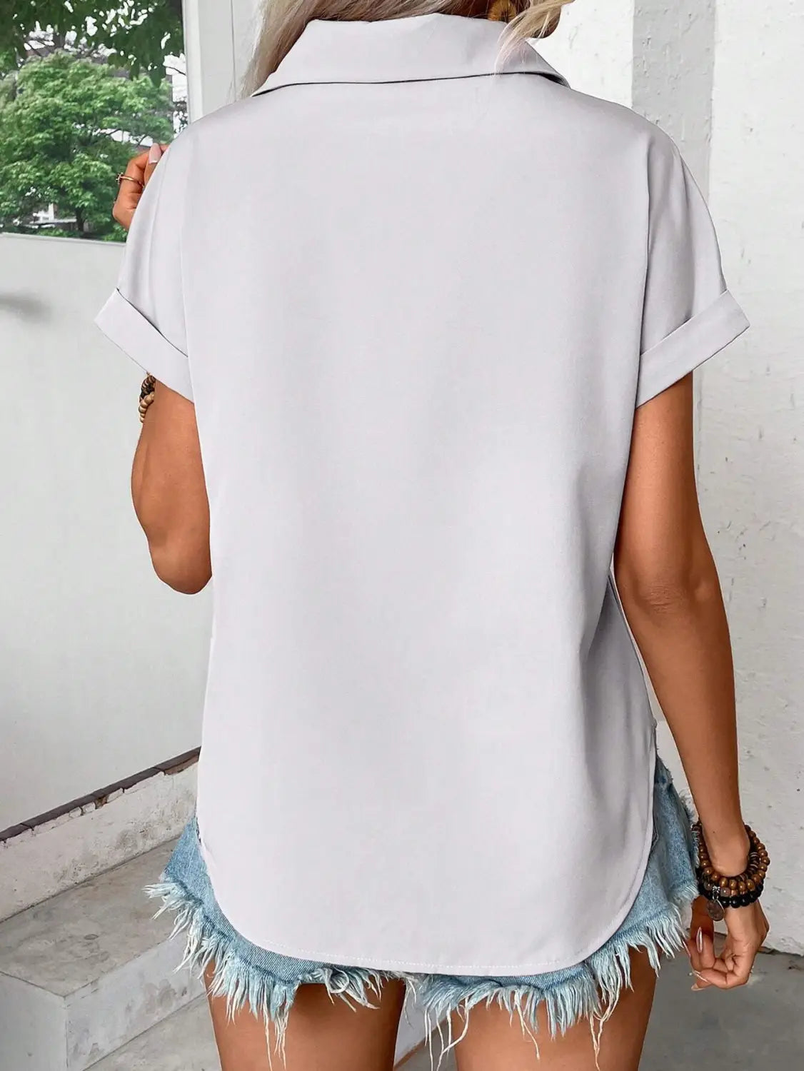 Light gray short sleeve button up blouse for women featuring a collar and rolled cuffs highlighting the sleeve length.