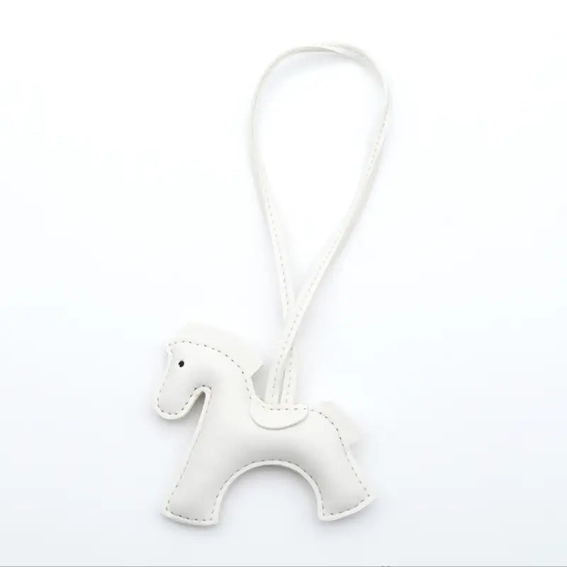 Porte-clés en cuir blanc en forme de cheval avec détails cousus et une boucle assortie pour la fixation.