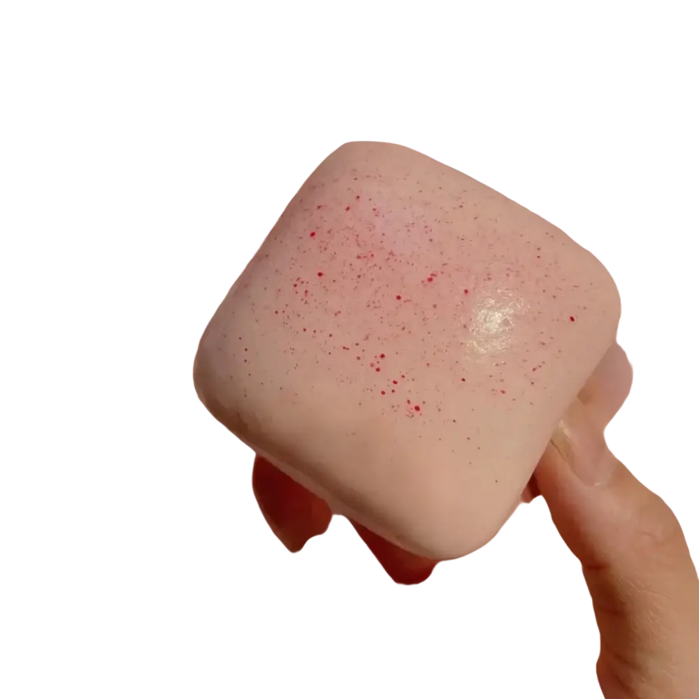 A front view of a soft pink square mini toast slow rising squishy with glittery finish and red speckles