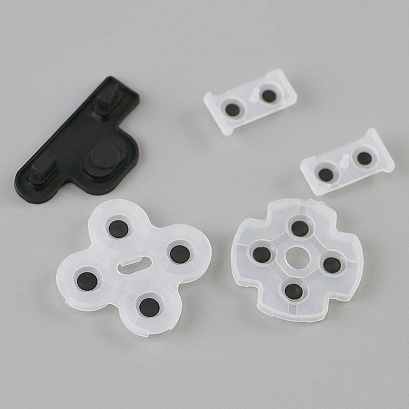 Set aus durchscheinend weißen und schwarzen leitfähigen Gummipads mit kreisförmigen Vertiefungen für die Tastenabdeckungen des PlayStation-3-Controllers.