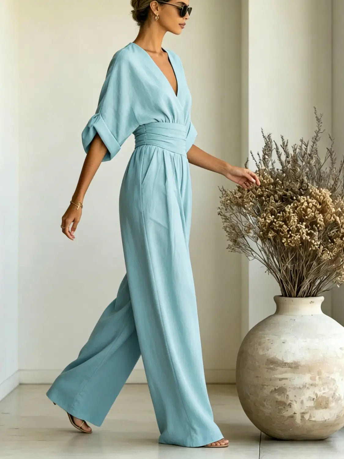 a light blue flowing wide-leg jumpsuit with a v-neckline and cinched waist designed for elegant and comfortable wear