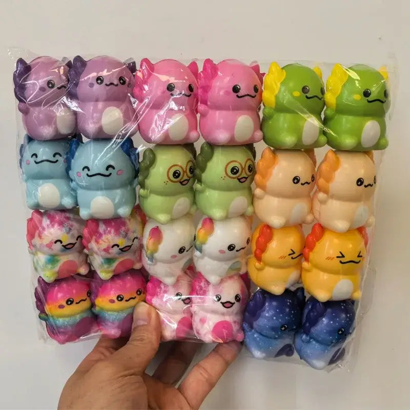 Eine Sammlung farbenfroher Pastell- und Axolotl- sowie Drachen-Quetschspielzeuge mit Kuscheloptik zur Stressreduktion, hergestellt aus weichem Material.