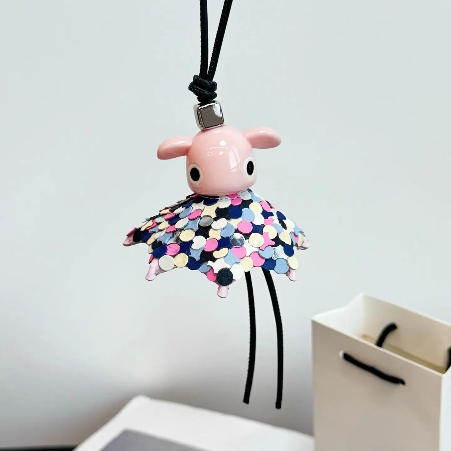 Llavero colgante para bolso con encanto de animales de cuero, tierno, de diseñador, con una figurita de cerámica de cerdito rosa, falda de lentejuelas de colores y correa colgante de cordón negro.