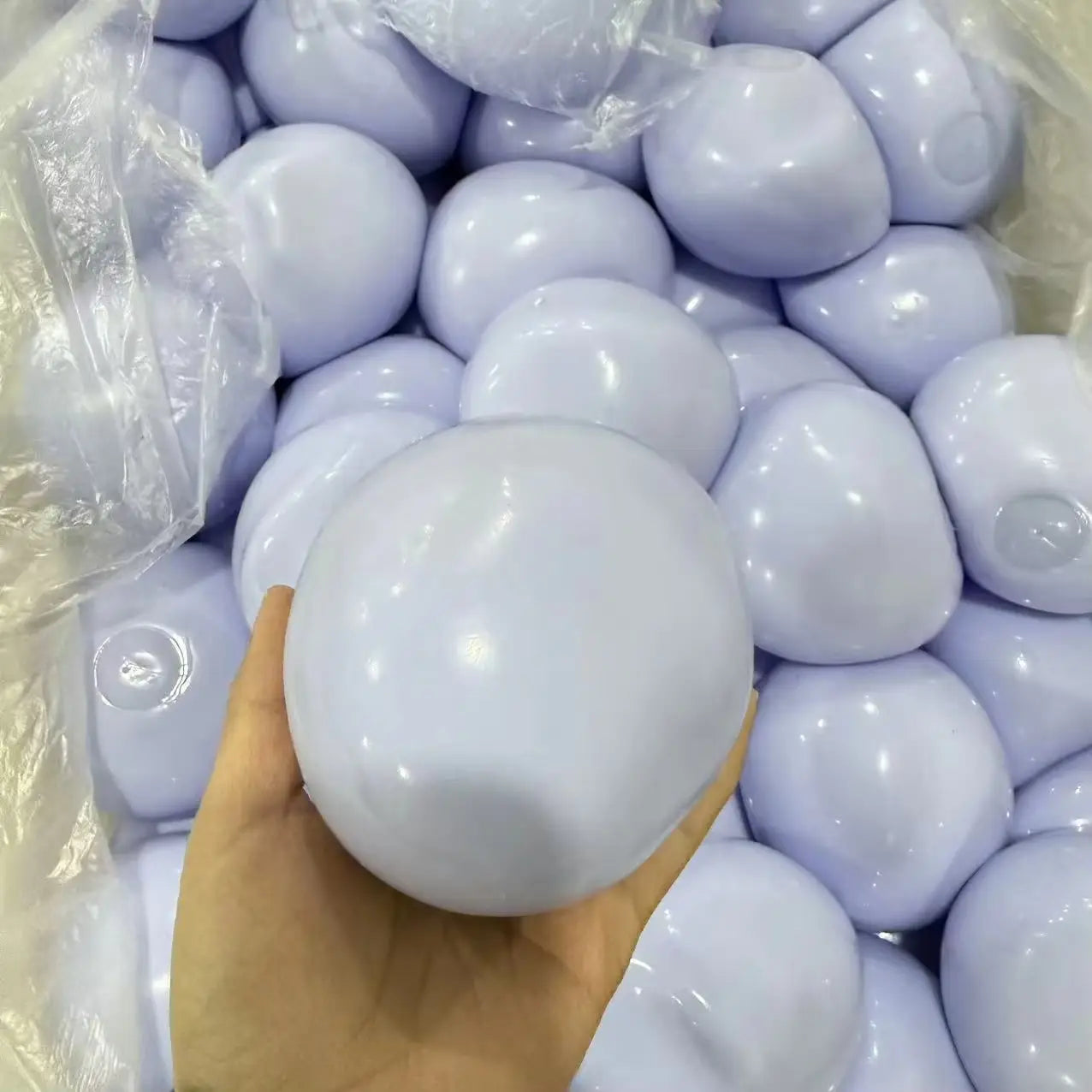 Ein glatter, glänzender, hellvioletter Kunststoff-Knetball zur Stressreduktion als sensorisches Spielzeug, in einer Hand gehalten.