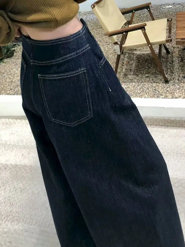 Pantalones vaqueros de tiro alto y pierna ancha de denim azul oscuro para mujer, con costuras blancas y una silueta de pierna ancha.