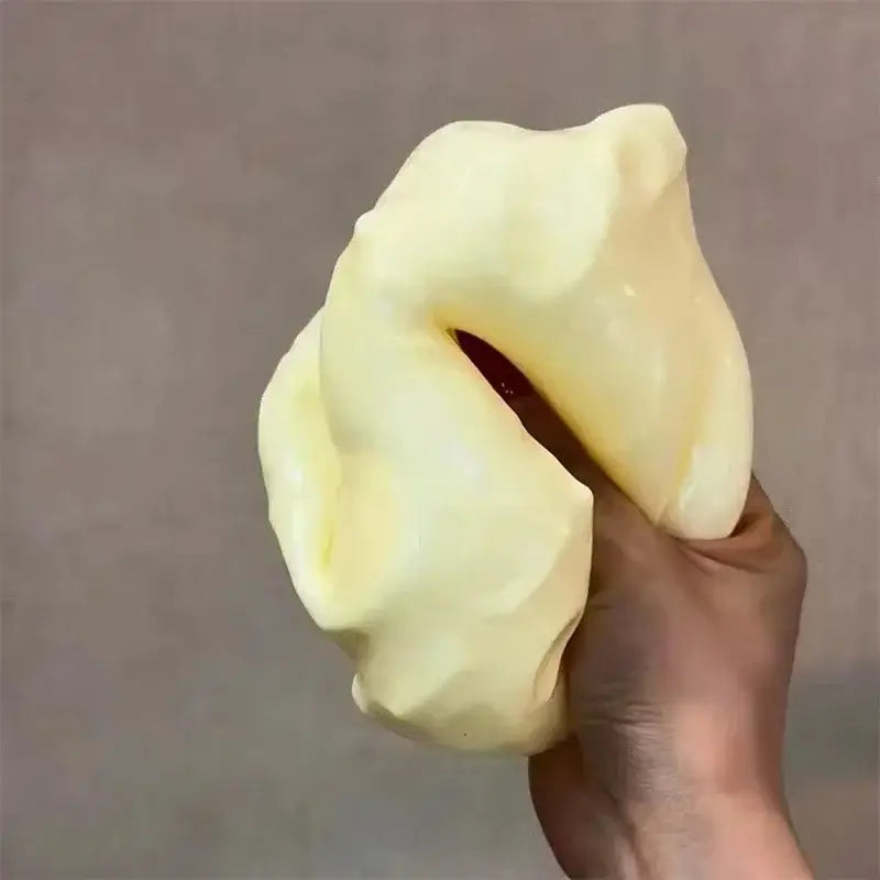 Un juguete antiestrés viscoso suave y elástico, de color amarillo pálido, que se sostiene en una mano.