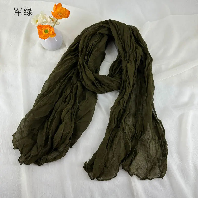 Écharpe en coton et lin plissé vert olive, avec une texture douce froissée et un tissu léger et transparent.
